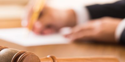 Closeup of Gavel with Lawyer Writing on Background